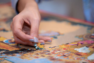 Close-up of woman hand arranging jigsaw pieces on table