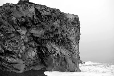 Rock formation by sea against sky