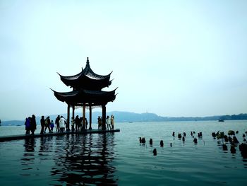 Group of people in water against clear sky