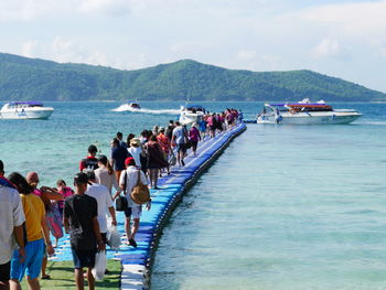 People on boats in sea against sky