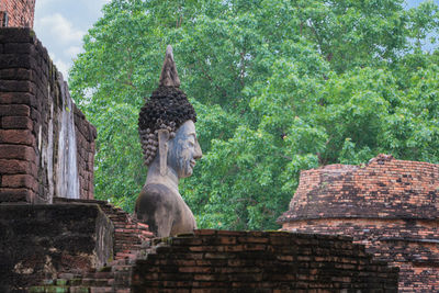 Statue amidst trees and buildings against sky