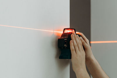 A young man uses a laser level on the wall.