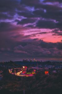 High angle view of illuminated cityscape against dramatic sky