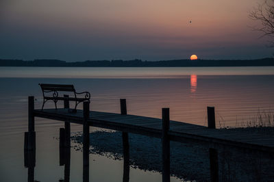 View of jetty in calm sea at sunset