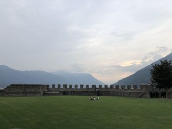 Built structure on landscape against cloudy sky