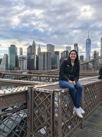 Portrait of smiling young woman sitting on brooklyn bridge