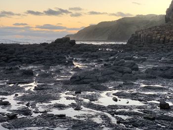 Rocks on shore against sky during sunset