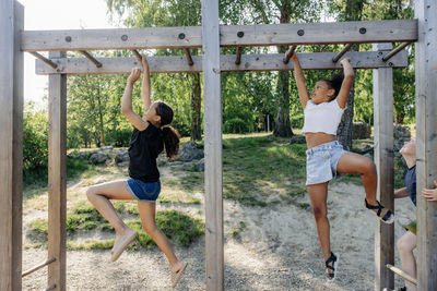 Girls practicing monkey bars while playing during summer camp