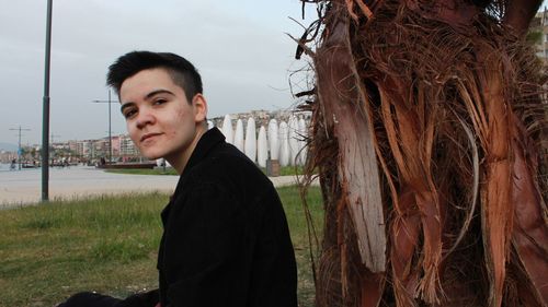 Portrait of young man standing against sky
