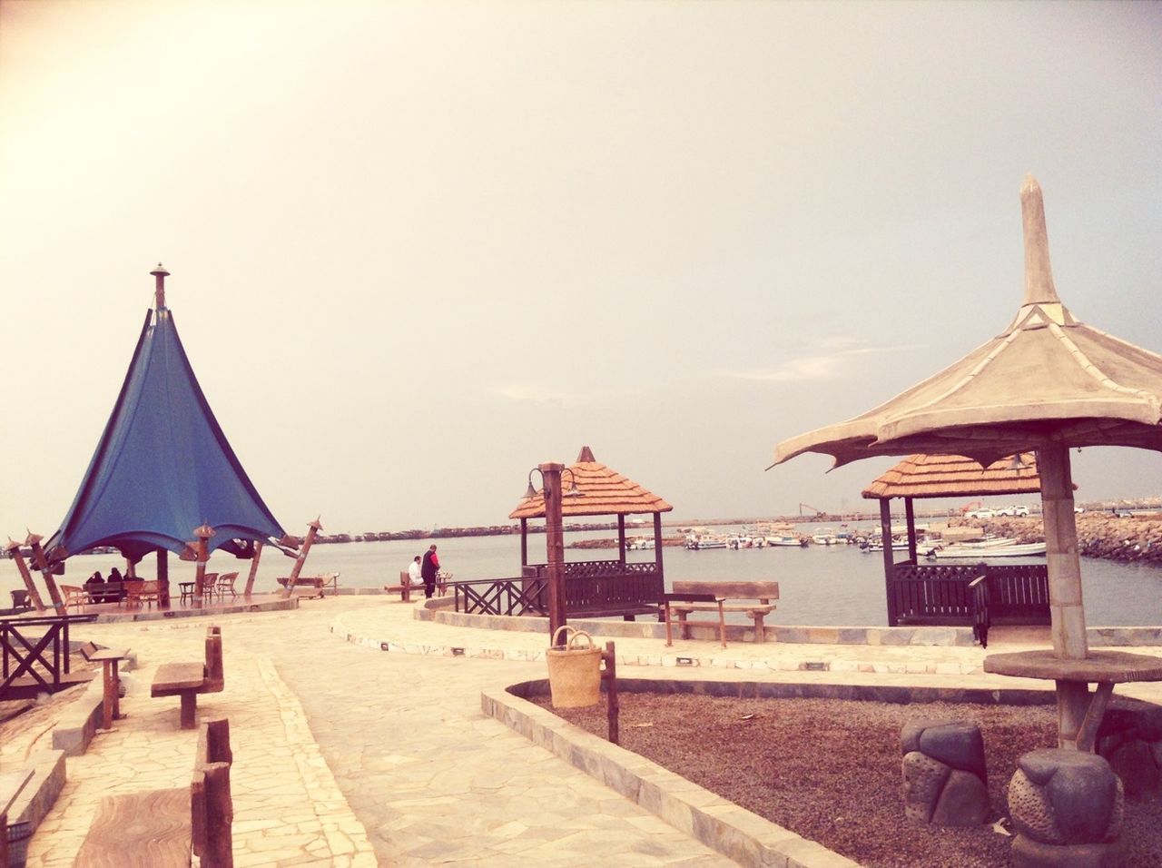 sea, beach, built structure, water, sky, clear sky, architecture, sand, building exterior, horizon over water, parasol, incidental people, outdoors, day, nautical vessel, shore, copy space, beach umbrella, travel destinations, roof