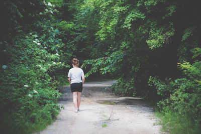 Full length of woman walking on footpath at forest