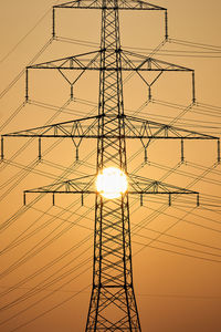 Low angle view of silhouette electricity pylon against sky during sunset