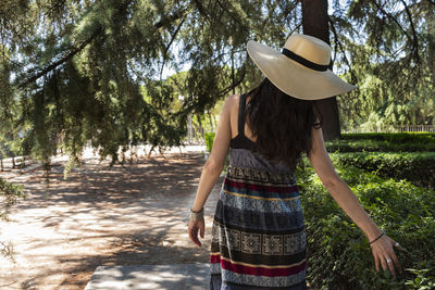 Rear view of woman wearing hat standing by tree