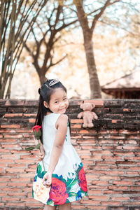 Portrait of cute girl standing against brick wall