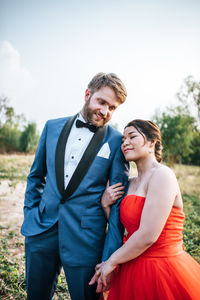 Smiling groom with bride against sky