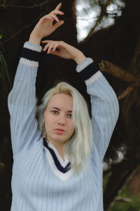 Portrait of beautiful young woman with arms raised