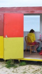 Rear view of woman sitting on bench against building