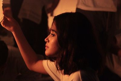 Side view of young woman looking away at night