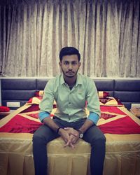 Portrait of young man sitting on sofa at home