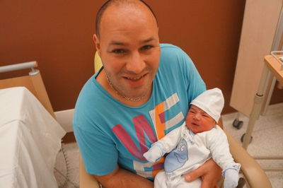 Portrait of happy father holding newborn baby in hospital