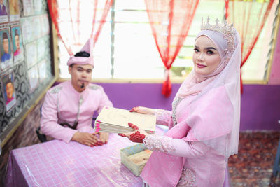 Young man with woman standing against pink wall