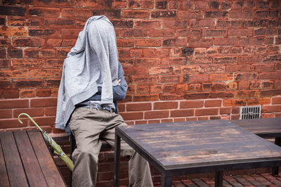 Man standing against brick wall