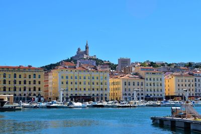 View of buildings by canal against clear blue sky