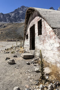 Abandoned building by rocky mountain against sky