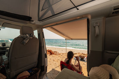 Rear view of woman sitting on beach