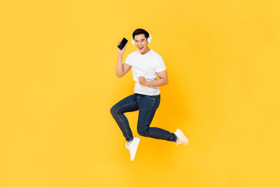 Portrait of smiling young woman against yellow background