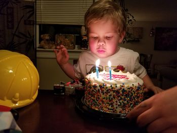 Cute boy blowing birthday candles at home