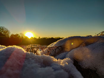 Snow covered land against sky during sunset