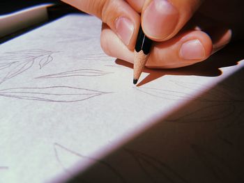 Cropped hand of person drawing on paper with pencil 