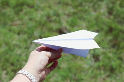 Cropped hand holding paper airplane