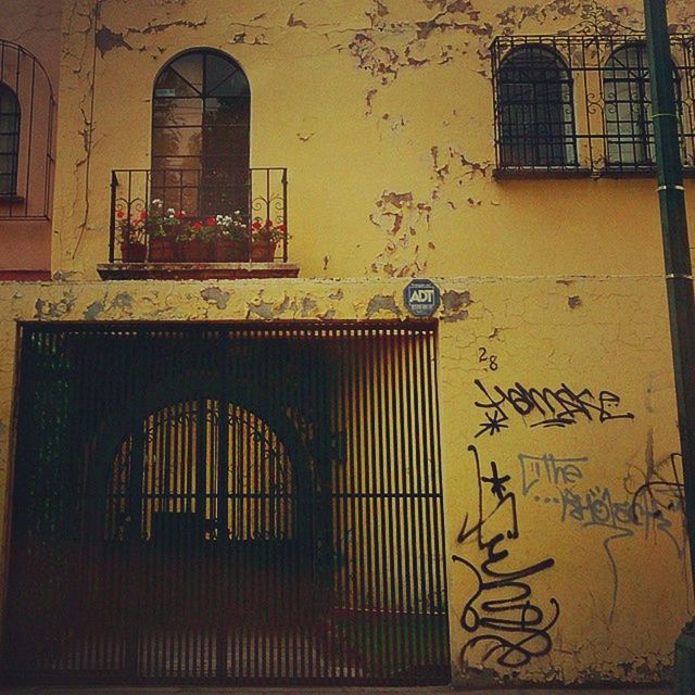 architecture, building exterior, built structure, window, yellow, building, door, residential structure, residential building, house, closed, text, low angle view, wall - building feature, brick wall, outdoors, shutter, western script, day, no people