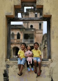 Full length of siblings sitting on wall