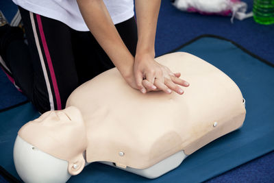 Midsection of paramedics performing cpr on mannequin