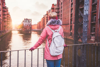 Woman standing by railing against canal in city