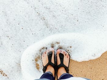 Low section of person standing on sand