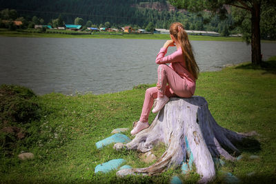 Rear view of woman with arms raised standing by lake