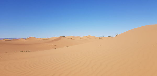 Sand dunes in desert against clear blue sky