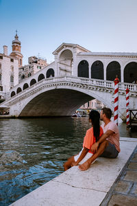 People sitting on bridge over water