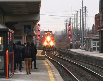 People at railroad station platform against sky