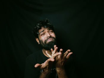 Young man looking away against black background