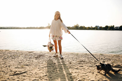 Full length of woman with dog standing at beach