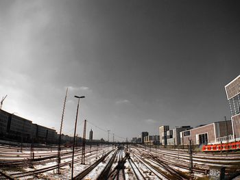 Railroad tracks in city against sky during winter