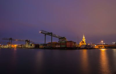 Illuminated pier by sea against sky at night