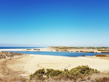 Scenic view of beach against clear blue sky