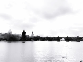 View of buildings by river against cloudy sky