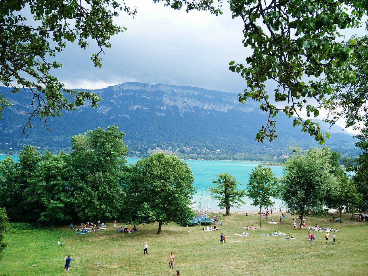 tree, large group of people, mountain, leisure activity, lifestyles, water, scenics, men, vacations, tranquil scene, sky, beauty in nature, person, tranquility, green color, nature, tourist, mixed age range, tourism